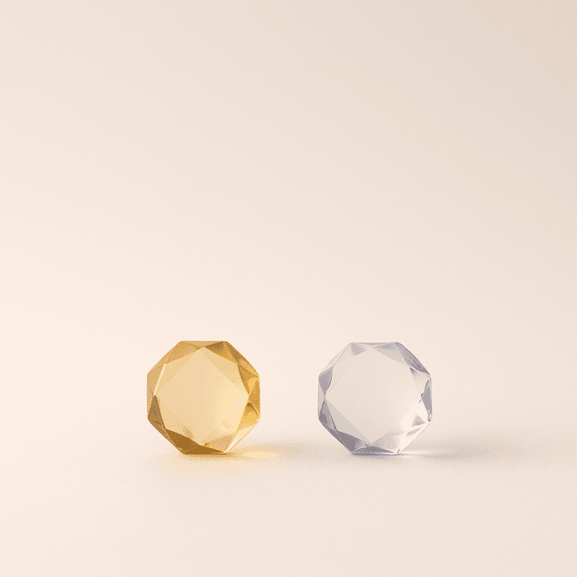 Dos cristales facetados uno junto al otro, uno dorado y otro neutro — comparar para elegir